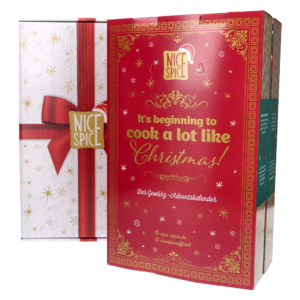 Klappbarer NICE SPICE Adventskalender im Buch-Stil, Ansicht der zugeklappten Vorderseite mit Wintermuster auf rotem Hintergrund sowie ein weißer Umkarton mit bedruckter roter Schleife im Geschenk-Stil